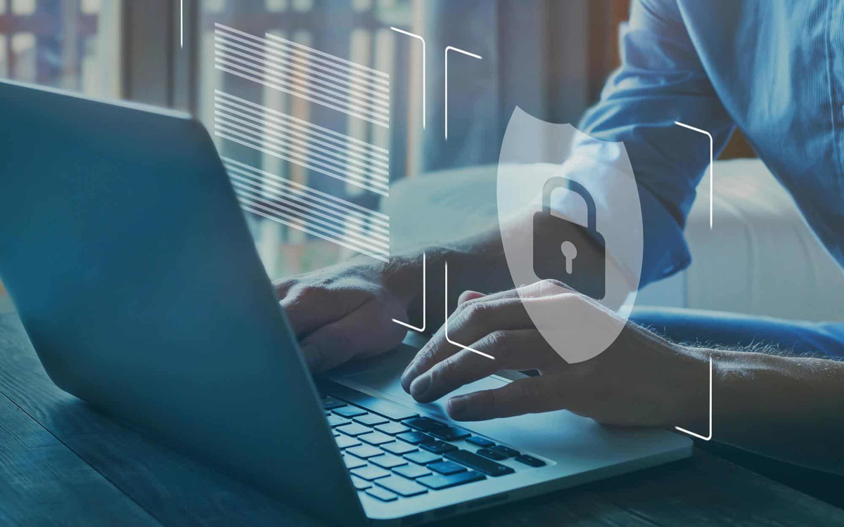 Man working on laptop with data protection icon floating around