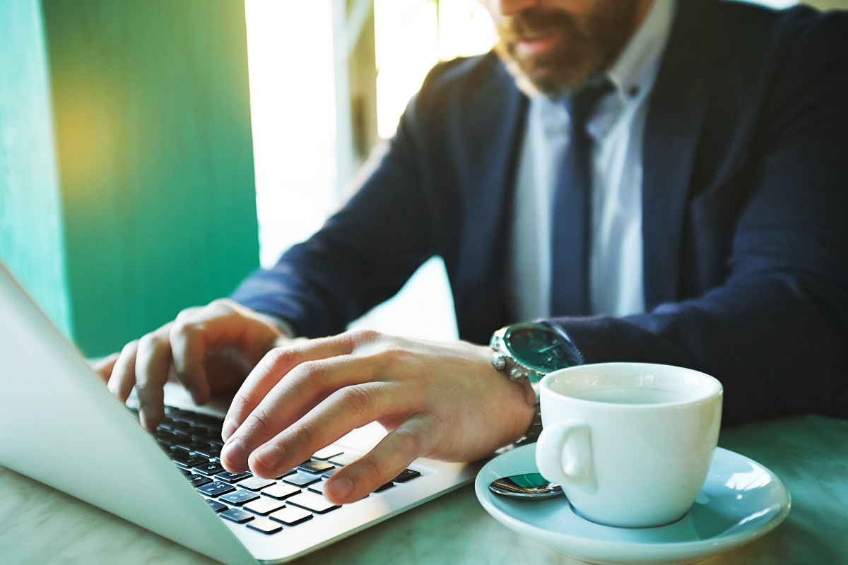 Man working on laptop with cup of coffee next to him