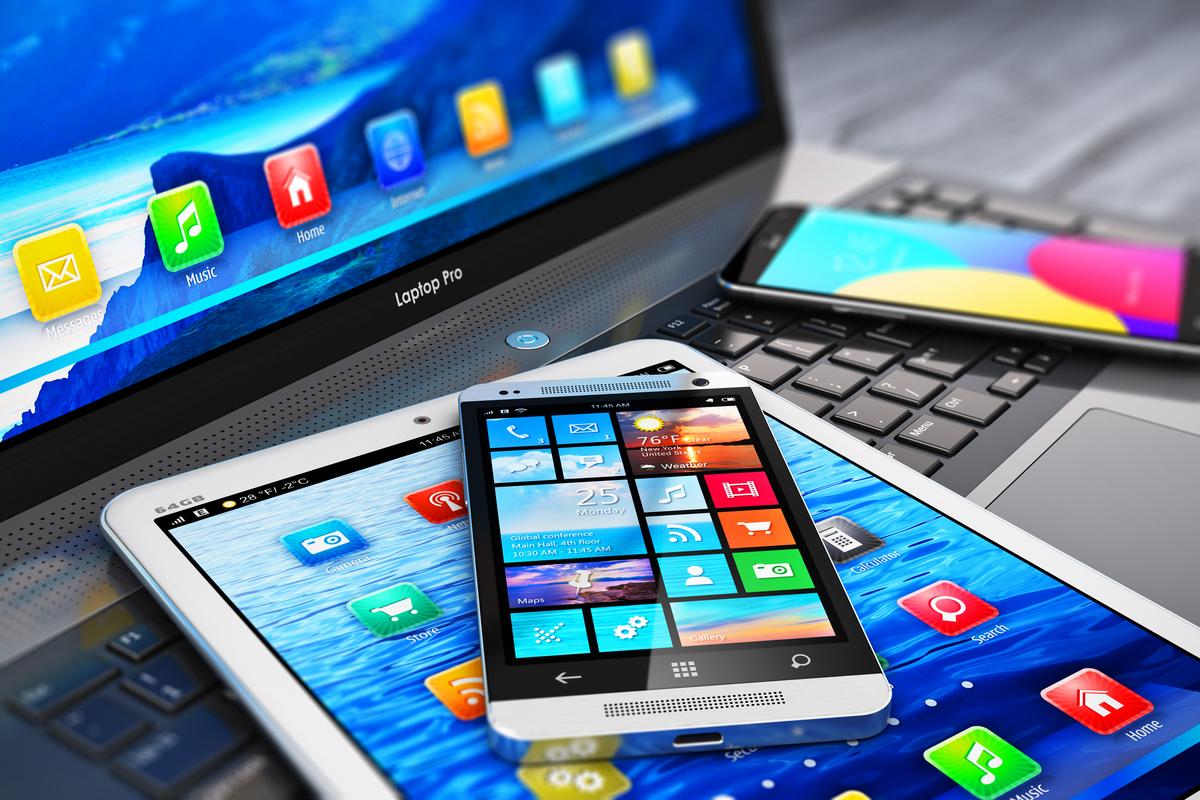 Laptop, tablet and smartphone on a desk, each showing a screen full of apps.